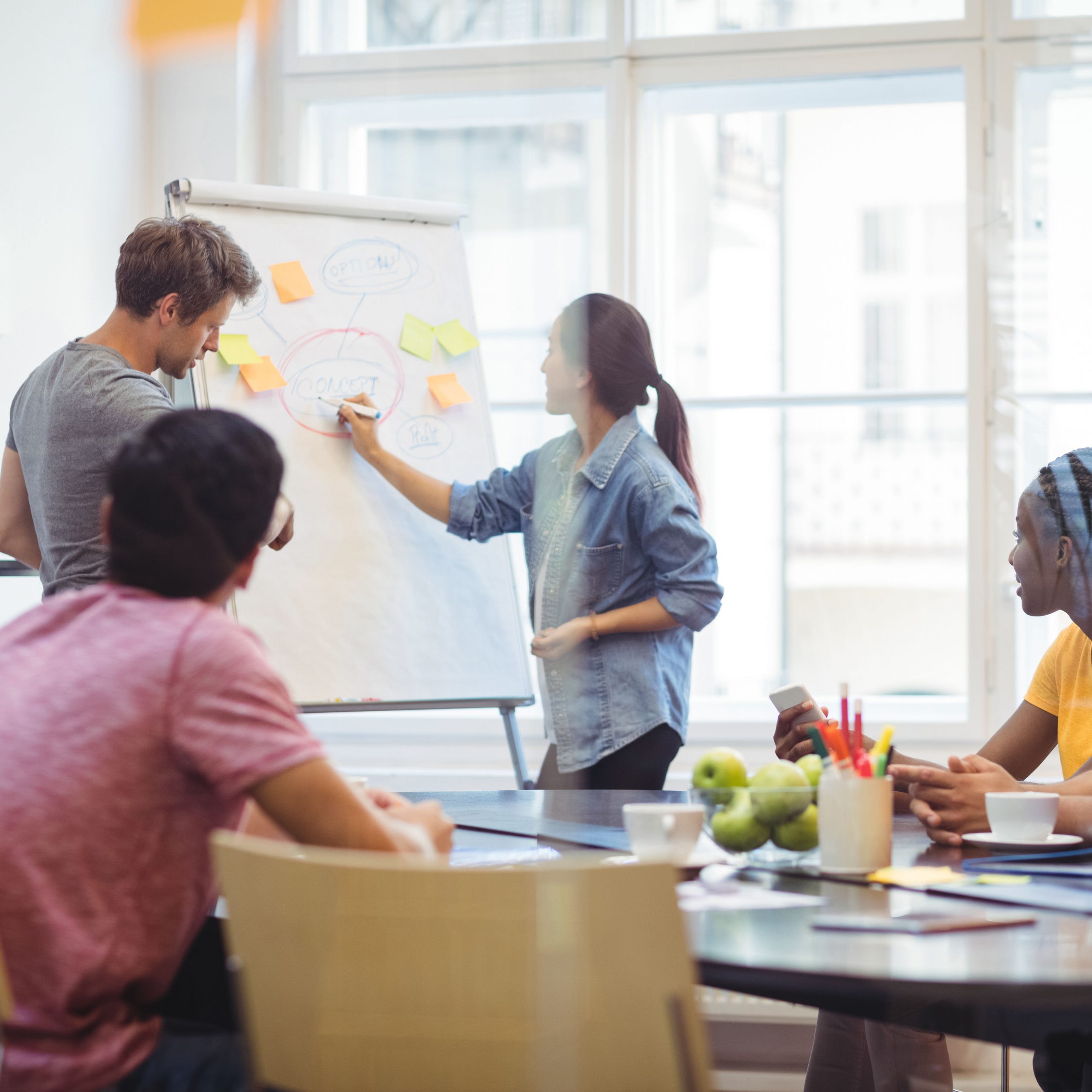 Business executives discussing with their colleagues on whiteboard during meeting at office